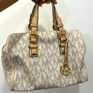 It is a michael kors bag. It is of skin and white color with golden tags.